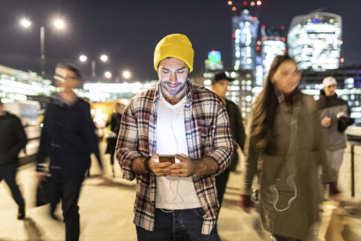 A man shops on a smart phone in a crown in Europe.