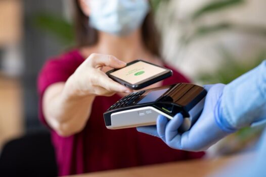 A woman making a contactless payment with her phone.