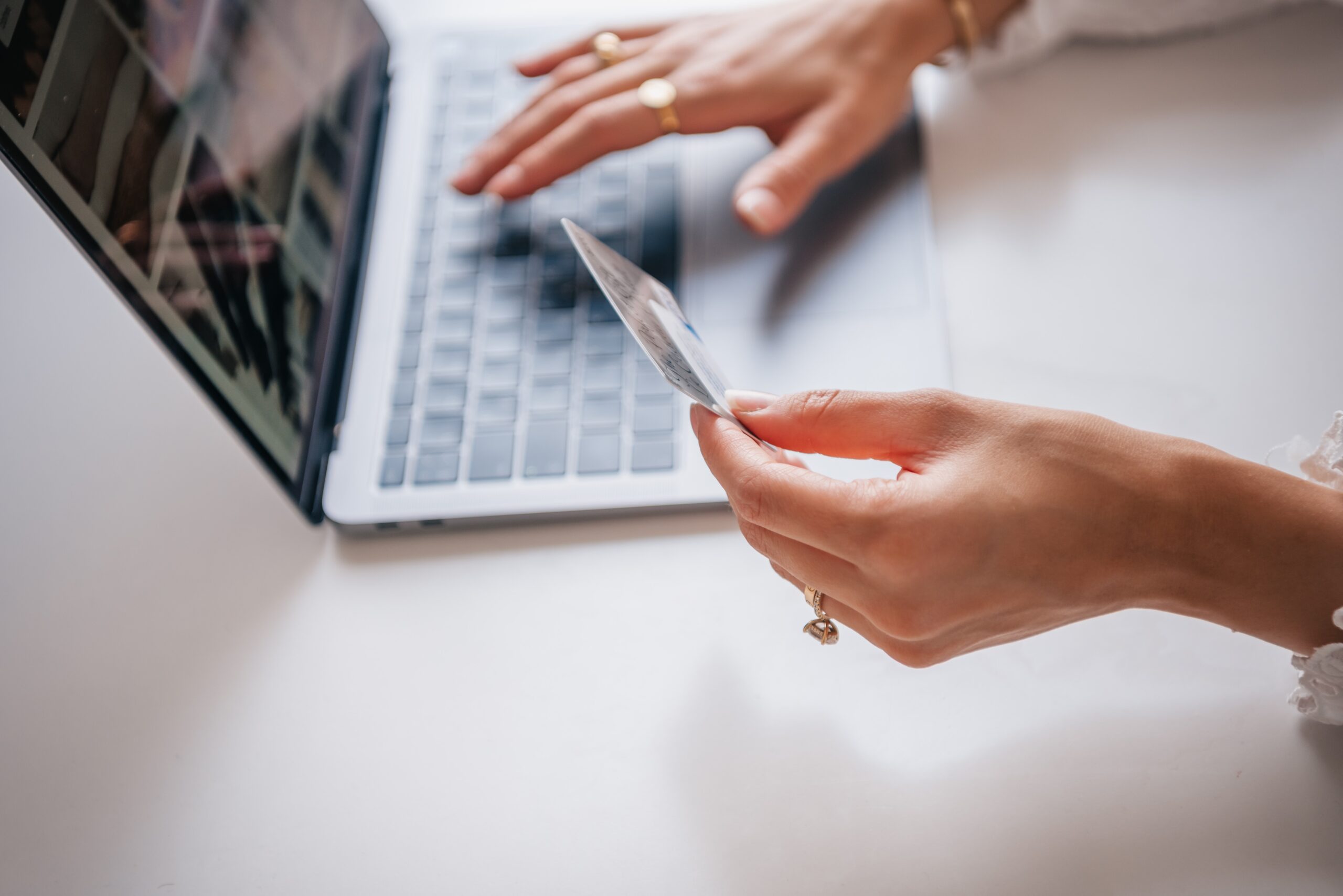 woman holds credit card while shopping on laptop and wonders if her card is PCI compliant