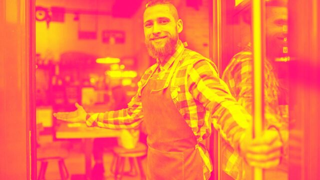 A smiling waiter with an apron greets restaurant guests and welcomes them depicting Forrester payments