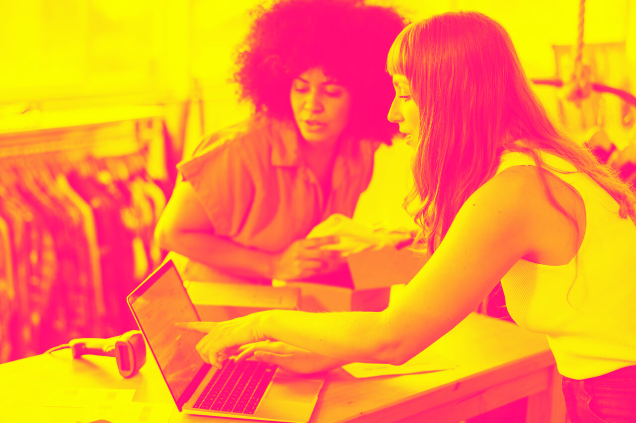 A woman explains to another woman through the computer what is the best payment method for e-commerce payment processing