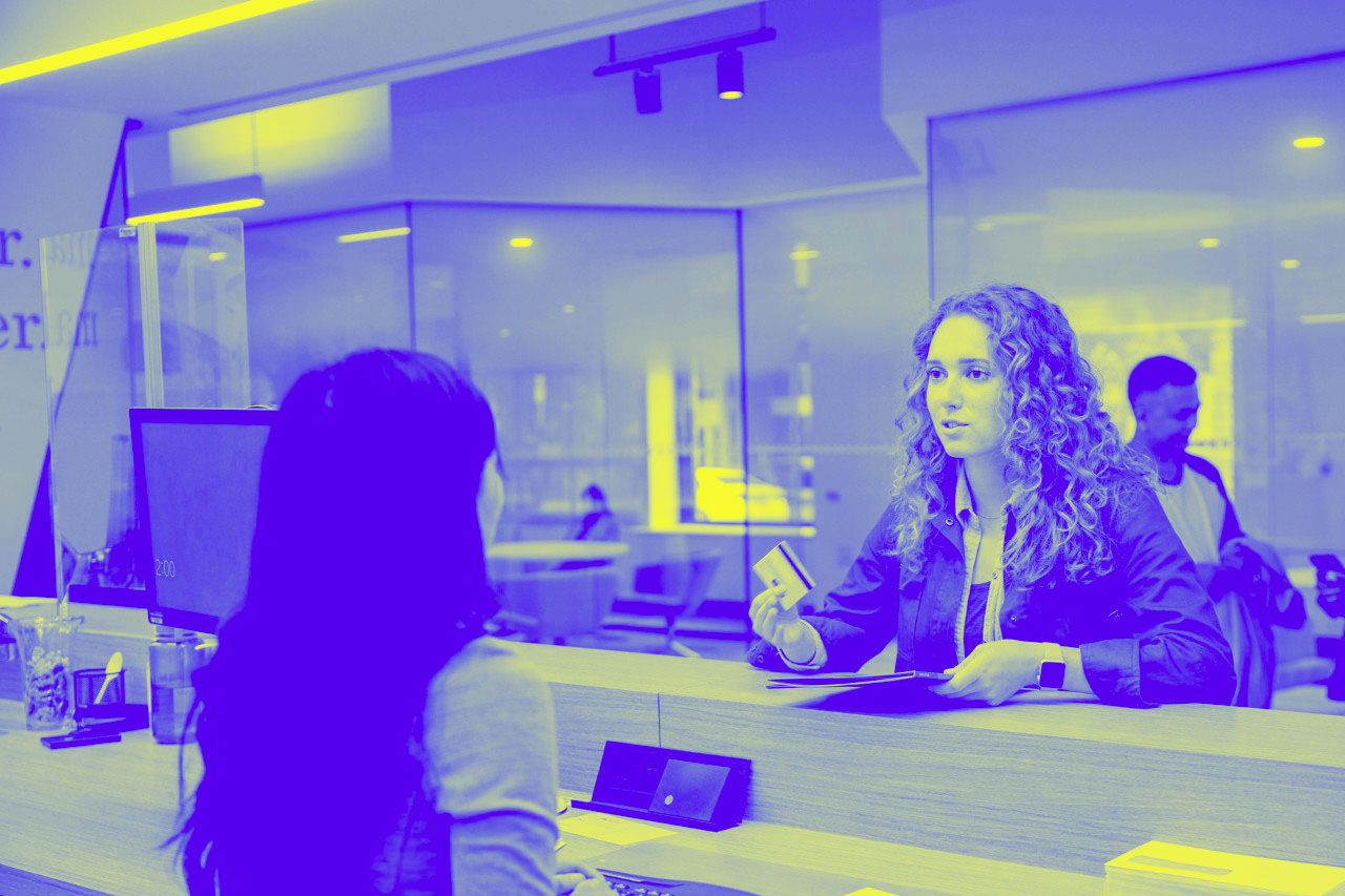 A woman pays at the bank teller, representing Pay by bank