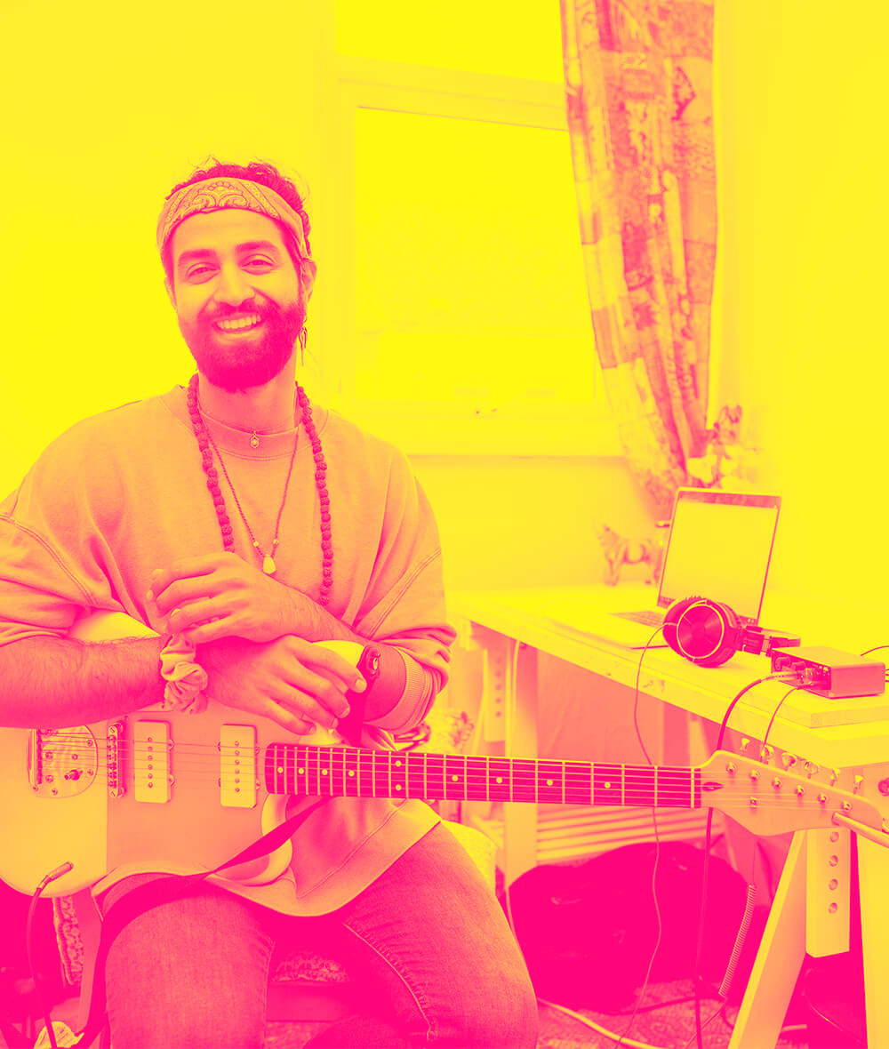 A man with a headband and a chain holding a guitar